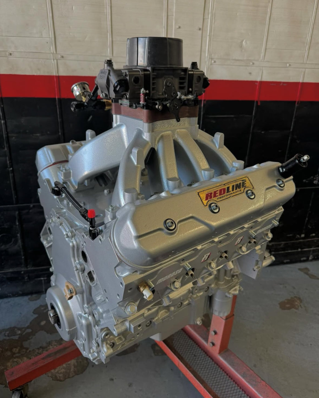 Car engine on a stand with a red and black striped wall in the background