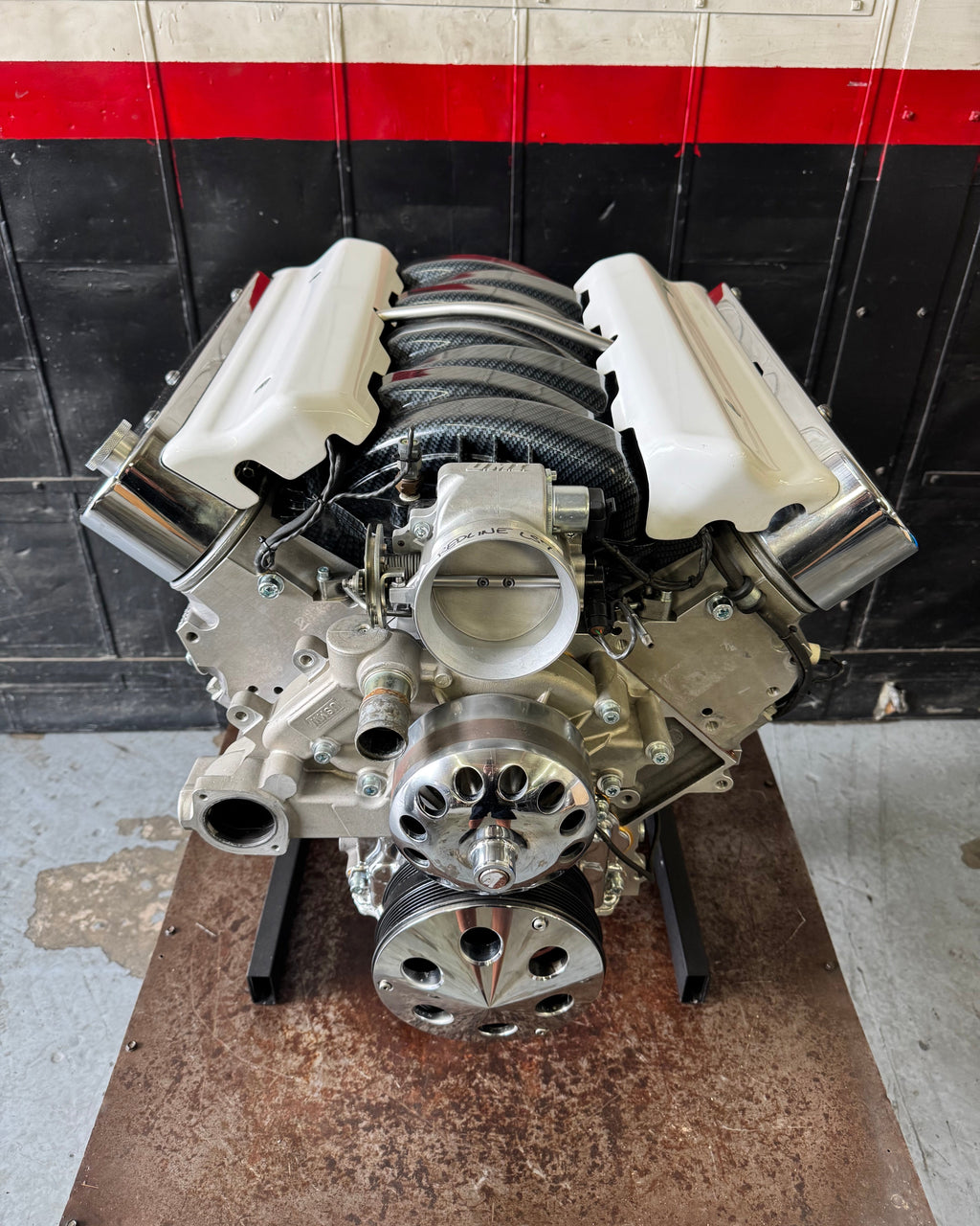Car engine on a stand with a red and black striped wall in the background