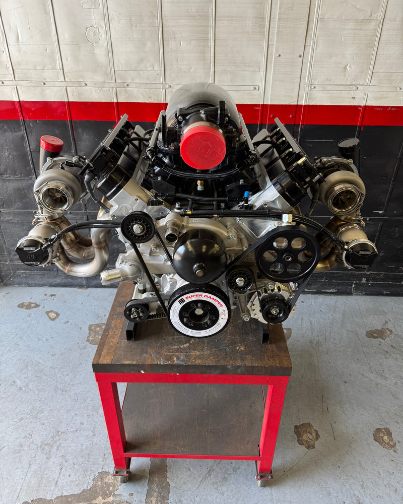 Engine on a stand in a workshop setting with a red and gray wall.