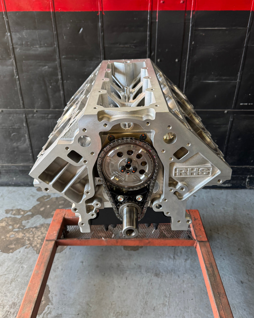 Engine block on a stand against a black and red wall.